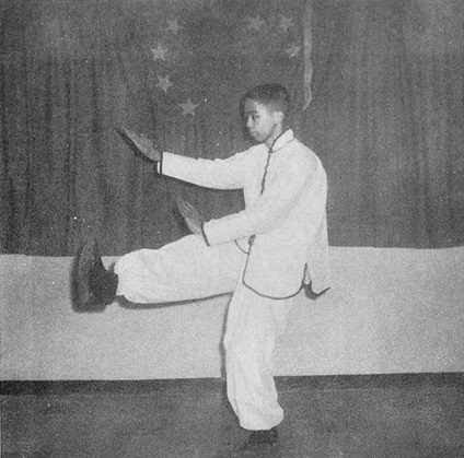 Posture 15 : les paumes se séparant en diagonale, jambe droite qui ramasse — photographie de l’édition de 1972
