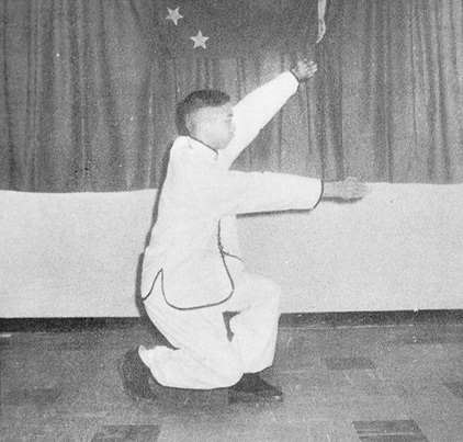 Posture 4 : pas de l’anneau à gauche, paumes poussant en avant, l’une haute l’autre basse — photographie de l’édition de 1972