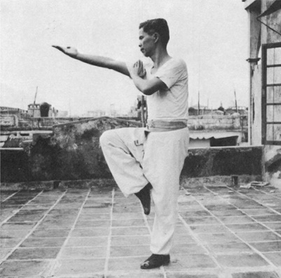 Posture 18a : le pied droit levé, la paume droite étirée vers le haut — photographie de l’édition de 1971