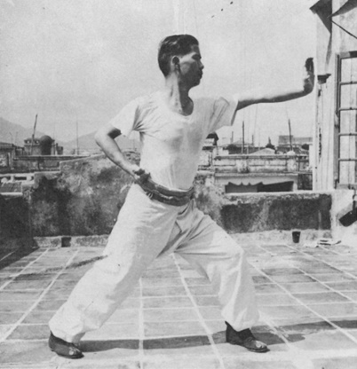 Posture 22 : pas d’arc à gauche, le poing droit à la taille, la paume gauche insérée devant — photographie de l’édition de 1971