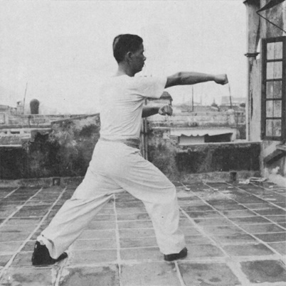 Posture 6 : la paume gauche scellant par-dessus l’épaule droite, le poing droit transperçant — photographie de l’édition de 1971
