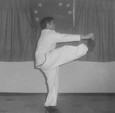 Posture 6 : la paume gauche s’écarte au-delà du poing droit, la main droite saisit vers la pointe du pied — planche de l’édition de 1972