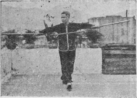 Posture 29, position de passage A (planche 29a) : le pied droit avancé en posture vide, le bâton entièrement déployé