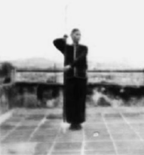 Posture 97, figure de transition A : les pieds joints, la main gauche reprenant la hampe — planche de l’édition de 1958