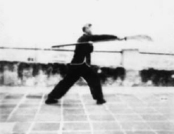 Posture 32, figure de transition : la hallebarde tenue à plat, la main gauche au creux du coude droit — planche de l’édition de 1958