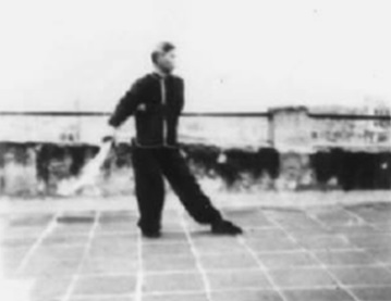 Posture 49, figure de transition : le pied gauche posé devant en pas vide, l’arme immobile — planche de l’édition de 1958