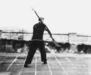 Posture 53, figure de transition A : le pied droit avancé en biais vers le sud-est, l’arme s’abattant — planche de l’édition de 1958