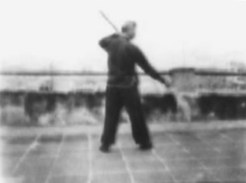 Posture 63, figure de transition A : le pied droit avancé vers le sud arrière, l’arme taillant — planche de l’édition de 1958