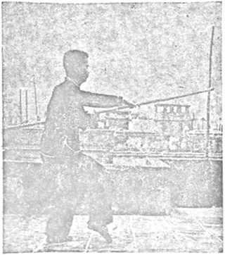 Posture 54 — Serrer le bâton sous le coude, poing qui perce (figure 54a)