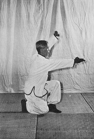Posture 7 : pas de l&rsquo;anneau à gauche, avant-bras gauche barré au-dessus de la tête, paume droite écartée vers la gauche — photographie de l&rsquo;édition de 1972