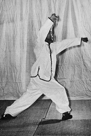 Posture 13 : ascension à droite reculée, avant-bras droit barré au-dessus de la tête, poing gauche au centre — photographie de l&rsquo;édition de 1972