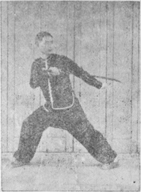 Posture 7, position de passage (planche 7a) : le pied droit ouvert vers l&rsquo;est, le sabre et la main crochue gauche légèrement écartés