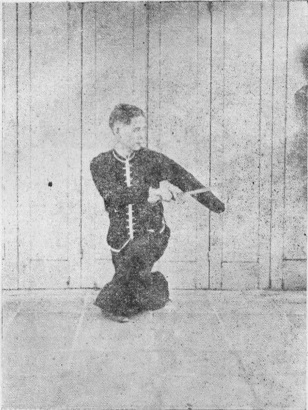 Posture 15, figure finale (planche 15c) : la posture assise en torsion, le sabre descendu de l&rsquo;épaule droite à l&rsquo;épaule gauche, la main gauche soutenant le dos de la lame