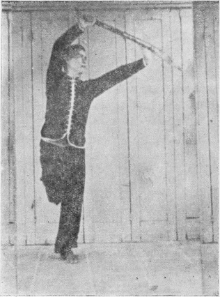 Posture 35, figure finale (planche 35b) : le pied droit levé, la paume gauche soutenant le dos de la lame, le sabre élevé en diagonale vers l&rsquo;extérieur