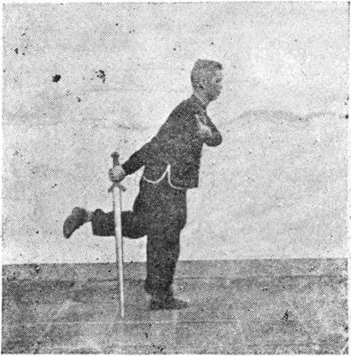 Posture 26, position de passage A (planche 26a) : le pied droit posé devant, l&rsquo;épée descendue vers l&rsquo;arrière, le pied gauche levé