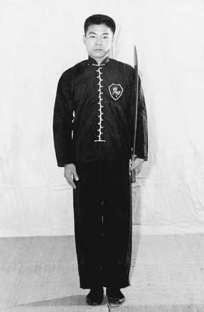 Posture 1 (planche 1) : debout, les pieds joints, le sabre porté de la main gauche le long de l&rsquo;épaule, la paume droite pendant près du corps, le regard tourné vers l&rsquo;ouest