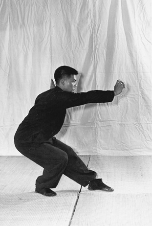 Posture 23, position de passage A (planche 23a) : le corps abaissé en posture vide basse, la main descendue