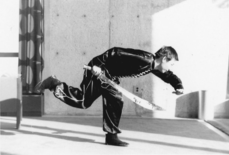 Posture 25, début de la roulade (planche 25a) : le corps penché, le sabre au-dessus de la tête, le pied droit levé vers l&rsquo;arrière