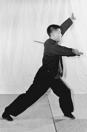 Posture 3 (planche 3) : le sabre ramené en travers après avoir enroulé autour de la tête et le dos, le pas posé à l&rsquo;est en posture de l&rsquo;ascension, la paume gauche au-dessus de la tête