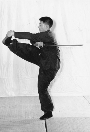 Posture 42 (planche 42) : le coup de pied tourbillon vers la gauche, le sabre en travers au-dessus de la tête